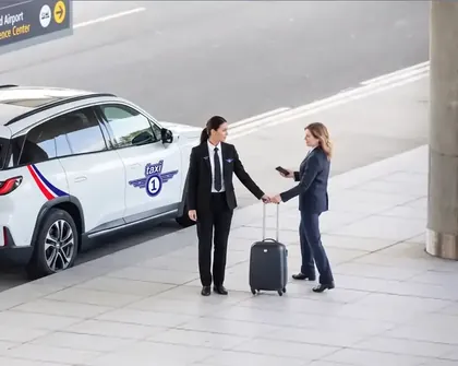 Taxi 1-sjåfør tar imot reisende med koffert på flyplassen